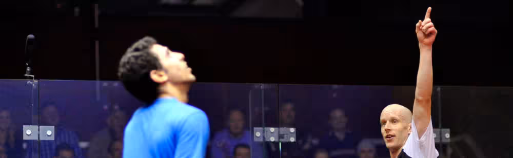 Two professional squash players looking at the ceiling.