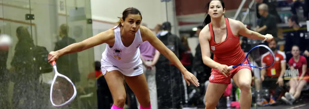 Two female squash players on the glass court
